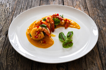 Shrimps salad with ginger and chili in mango sauce on wooden table
