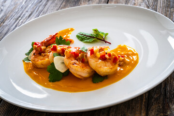 Shrimps salad with ginger and chili in mango sauce on wooden table
