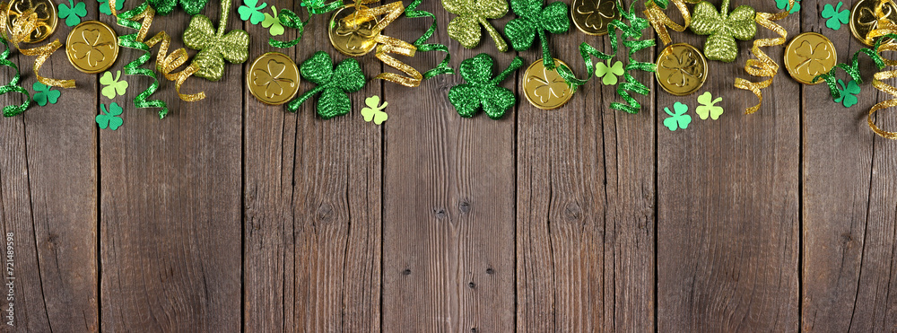Poster st patricks day top border of green shamrocks, gold coins and ribbon. above view over a rustic dark 