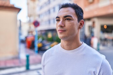 Young hispanic man looking to the side with serious expression at street