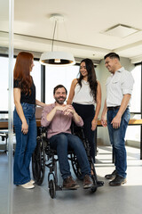 Man in a wheelchair feeling welcome and supported by their team members at an inclusive office