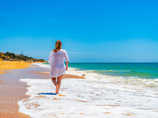 Beautiful woman walking on sunny beach Albufeira Algarve Portugal