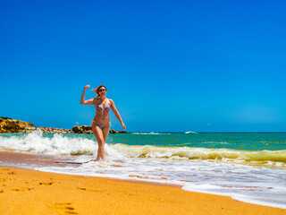 Fototapeta premium Beautiful woman walking on sunny beach Albufeira Algarve Portugal