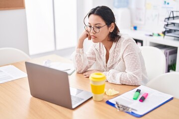 Young hispanic woman business worker using laptop with sad expression at office