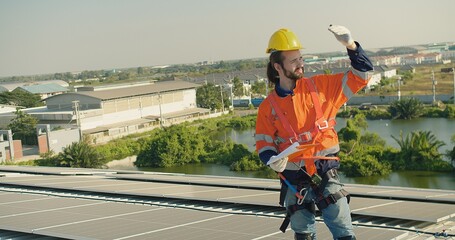 A solar technician Inspecting panels in safety gear examines solar installations on a sunny rooftop