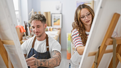 A woman and man artistically engaged in painting on easels within a bright, well-organized studio...