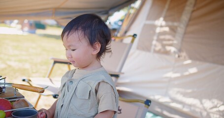 Joyful young toddler child enjoying a day at a camping site with family, smiling in a khaki outfit...
