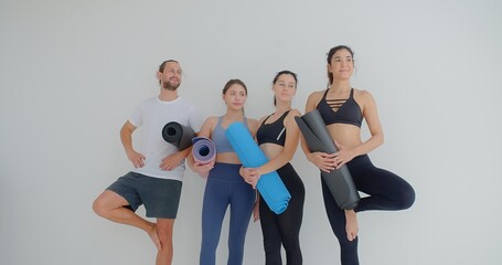 Obraz premium group of woman and man standing leaned on wall waiting for yoga class, before or after work out people in sportswear holds yoga mats looking happy and healthy, well-being, sports wellness concept