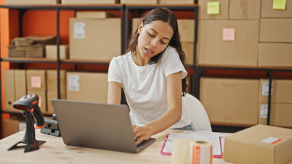 African american woman ecommerce business worker using computer talking on smartphone at office