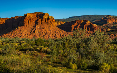 Red rock cliffs of Capitol Reef  national park illuminated by a strong sunlight in Utah early in the morning.