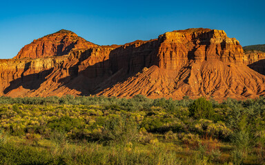 Red rock cliffs of Capitol Reef national park illuminated by a strong sunlight in Utah early in the morning.