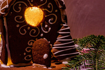 Ręcznie robiony domek z piernika: słodka ozdoba świąteczna,  domek uwieńczony cukrowym dachem, pełen ciepła i magii bożonarodzeniowego czasu, ze światełkiem w środku. - obrazy, fototapety, plakaty