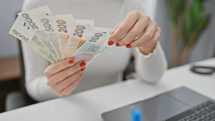 A young woman counts czech currency at her workplace, indicating finance, economy, or savings...