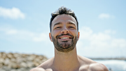 Young hispanic man tourist smiling confident shirtless at the beach