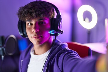 Young hispanic teenager streamer smiling confident make selfie by camera at gaming room © Krakenimages.com