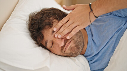 Young hispanic man lying on bed tired scratching eye at bedroom