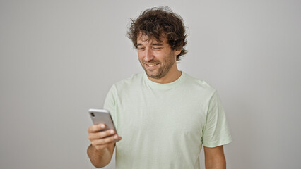 Young hispanic man smiling confident using smartphone over isolated white background
