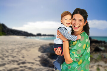 Smiling woman holding the child in her arms on a beach