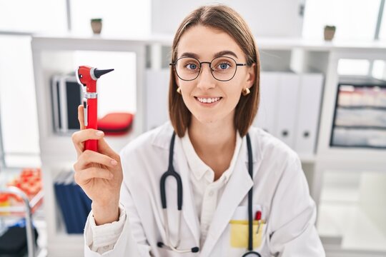 Young caucasian woman doctor holding otoscope at clinic