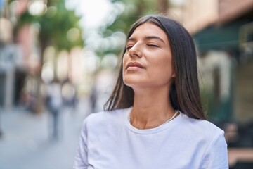 Young beautiful hispanic woman breathing with closed eyes at street - obrazy, fototapety, plakaty
