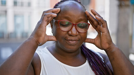 Stressed african american woman with braids, feeling headache ache on urban street, showcasing...