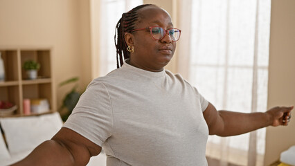 Plus size african american woman meditating, taking deep breaths in cosy bedroom, awake and looking...