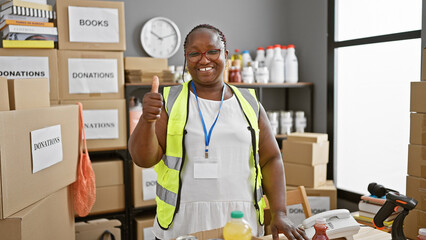 African american woman volunteer doing thumb up gesture smiling at charity center