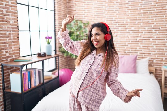Young beautiful arab woman listening to music and dancing at bedroom