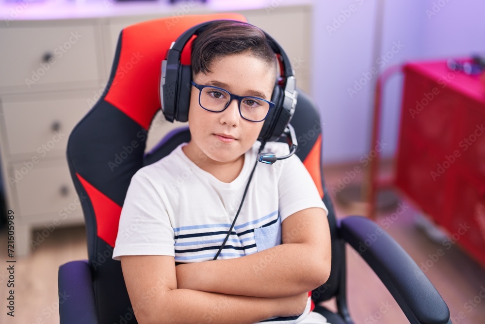 Sticker adorable hispanic boy streamer sitting with arms crossed gesture at gaming room