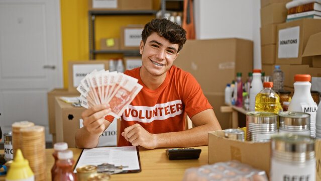 Smiling young hispanic teenager joyfully volunteers at charity center, confidently holding iceland krona banknotes