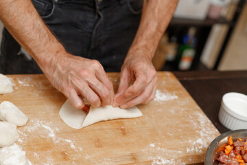 A young guy cooks from dough at home. Manti dumplings