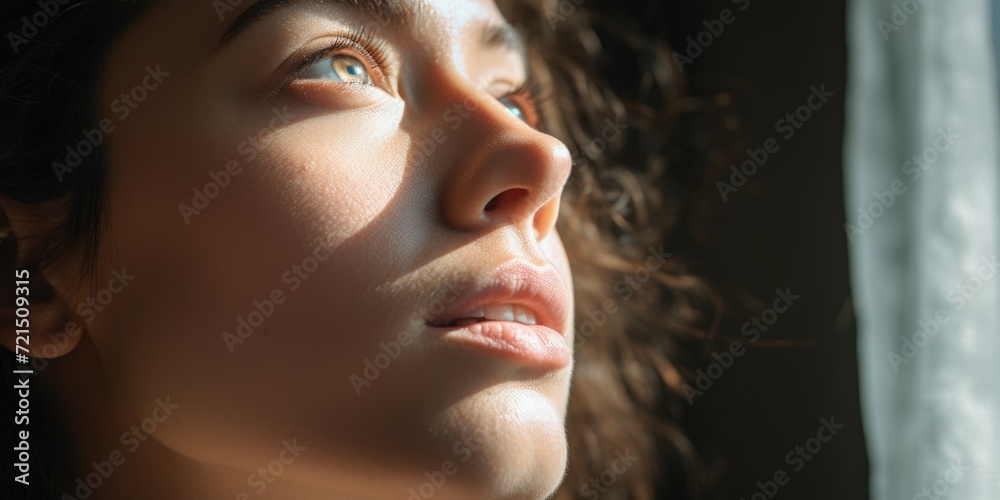 Poster a close-up of a woman looking out a window. this image can be used to depict curiosity, introspectio