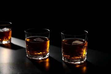 Two glasses of whiskey with ice on a black background, selective focus