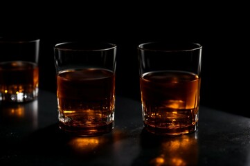 Two glasses of whiskey with ice on a black background, selective focus