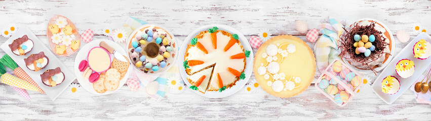 Easter or spring dessert food table scene. Top view over a white wood banner background. Lemon tart, cupcakes, Easter egg and carrot cakes and an assortment of sweets. - obrazy, fototapety, plakaty
