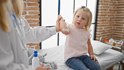 Cute little girl patient gets a band-aid on her arm by a caring doctor at the medical clinic, together they make healthcare less scary!