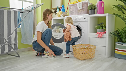Caucasian mother and daughter seriously concentrate on washing toys in the laundry room, a picture of family housekeeping - obrazy, fototapety, plakaty
