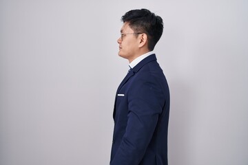 Young asian man wearing business suit and tie looking to side, relax profile pose with natural face...