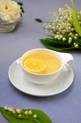 romantic image of herbal tea with lemon and lily of the valley flowers close up