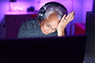 Middle age grey-haired man streamer stressed using computer at gaming room