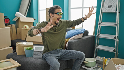 Young hispanic man playing video game using virtual reality glasses at new home