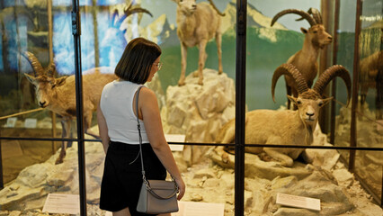 Young beautiful hispanic woman visiting natural history exhibition at Natural History Museum in...