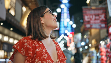 Capturing the joyful night, beautiful hispanic woman in glasses enjoying shinsekai street, laughter...