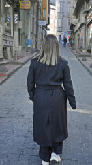 Back view of a young woman walking alone on a historic istanbul street, portraying urban exploration.