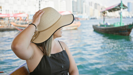 A young brunette woman enjoys a scenic boat ride on dubai creek, surrounded by the bustling city.