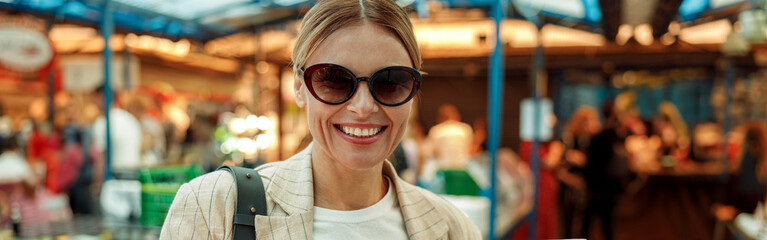 Smiling woman tourist is having a takeaway fast food lunch on food market and drink coffee