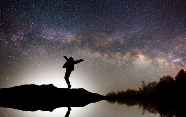 Silhouette of a hiker standing on the hill, on the milky way galaxy background.