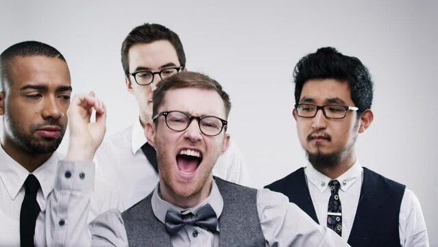 Friends, crazy or dancing in studio for party, goofy or joke with embarrassed by silly humour. Young men, diversity or dance at celebration with groom or unamused at wedding event by white background