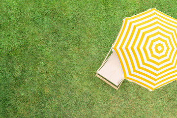 Yellow umbrella with deck chair on the green grass sunbathes at summer day. Top view, drone, aerial view. - 721527761