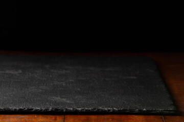 Black slate poured on a wooden table board background